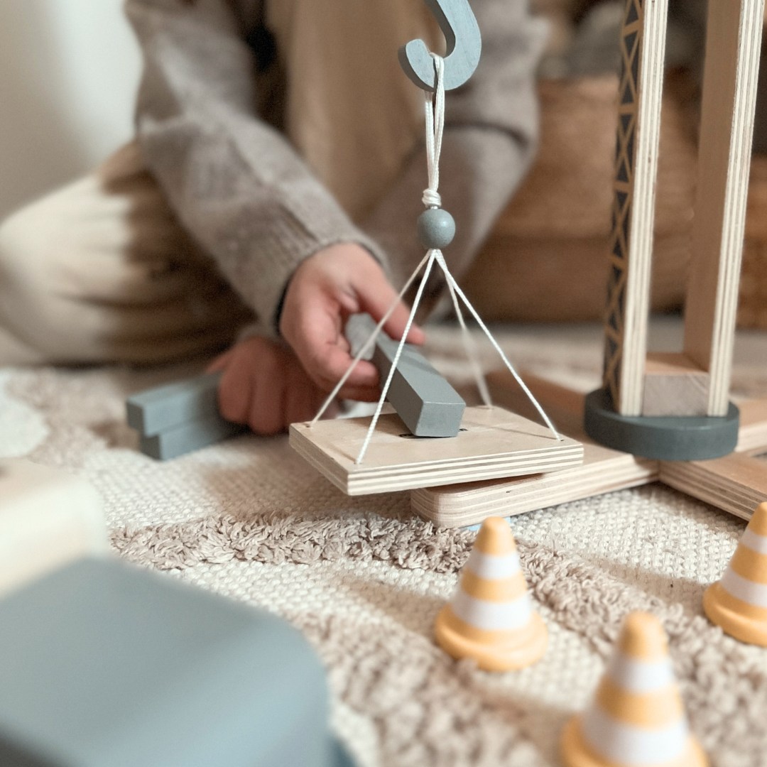 Medinė statybų aikštelė su dideliu mobiliuoju kranu ir transporto priemonėmis, bokštinis kranas